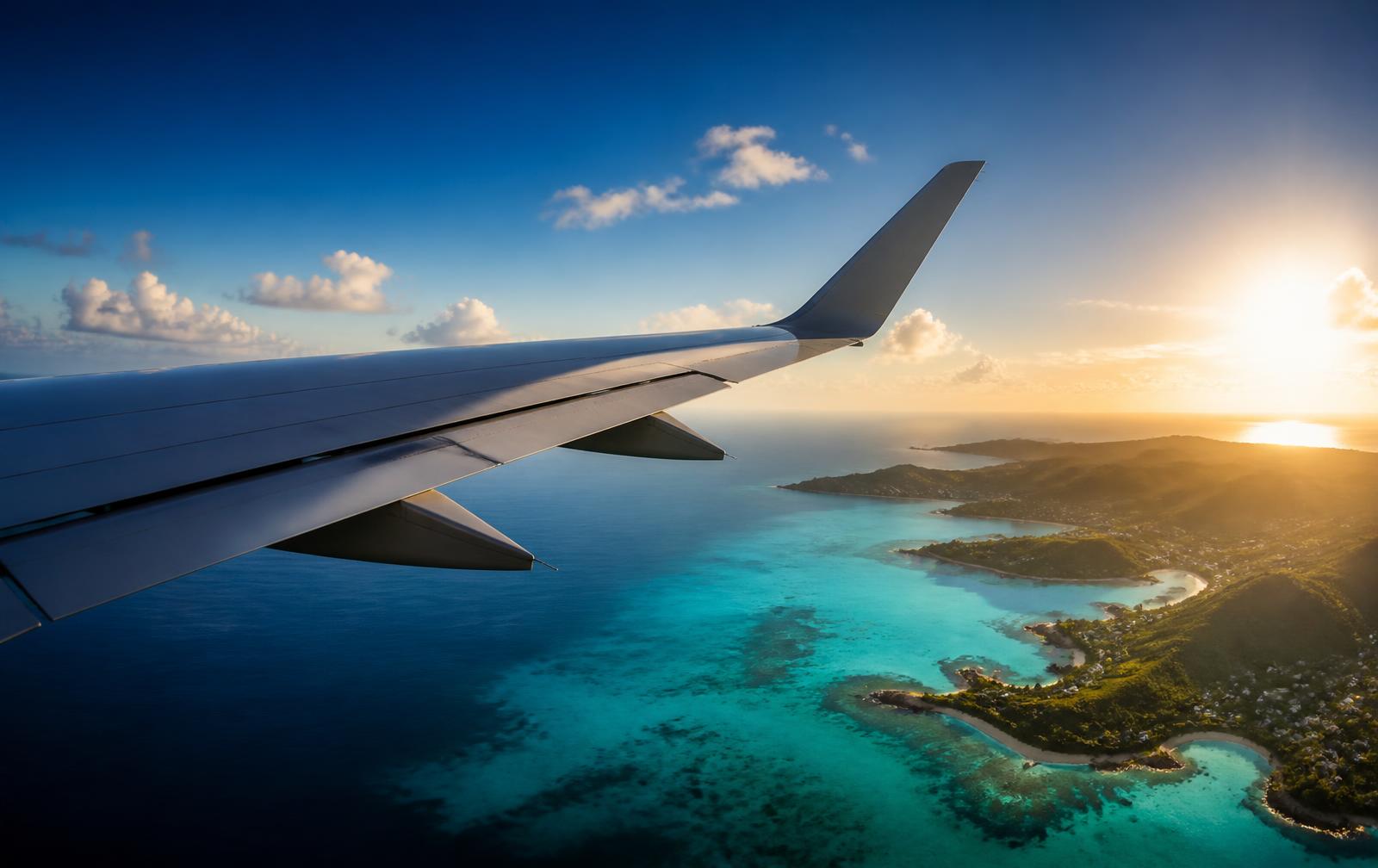 Asa de avião sobrevoando o litoral caribenho ao pôr do sol